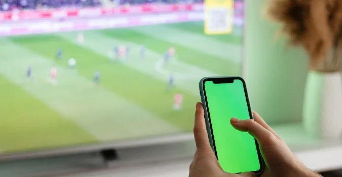 Apostando en directo en el móvil mientras se mira un partido